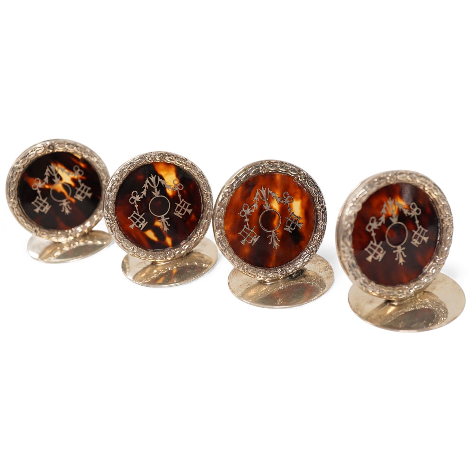 A set of four George V silver and tortoiseshell pique circular menu holders, by William Comyns, Birmingham, 1912/13, height 40mm.